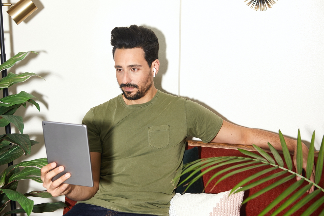 a man sitting on a comfortable chair looking at his mobile tablet