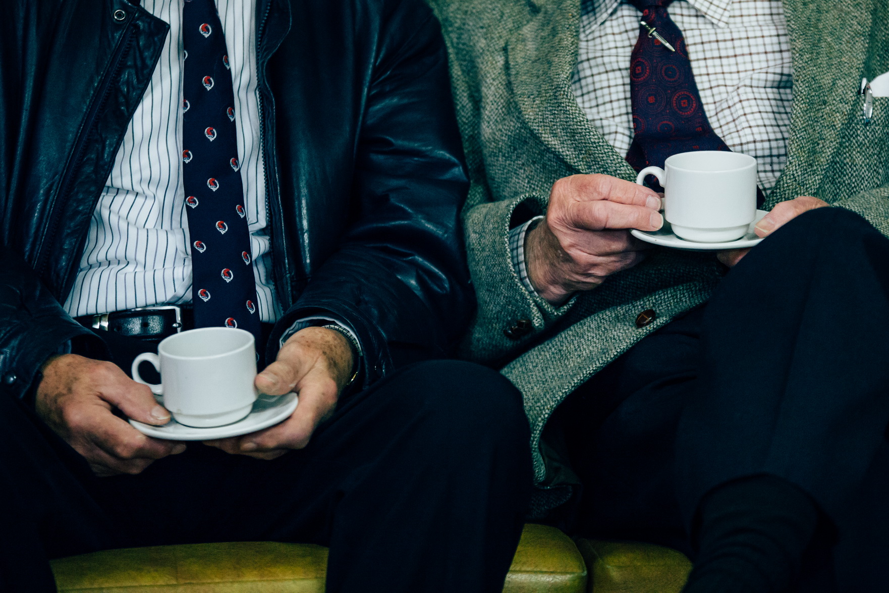 two old men on a bench drinking coffee