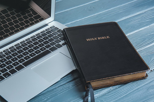 Words: A Bible next to a laptop computer