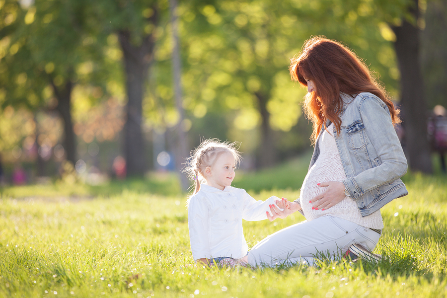 expectant mother and daughter in park