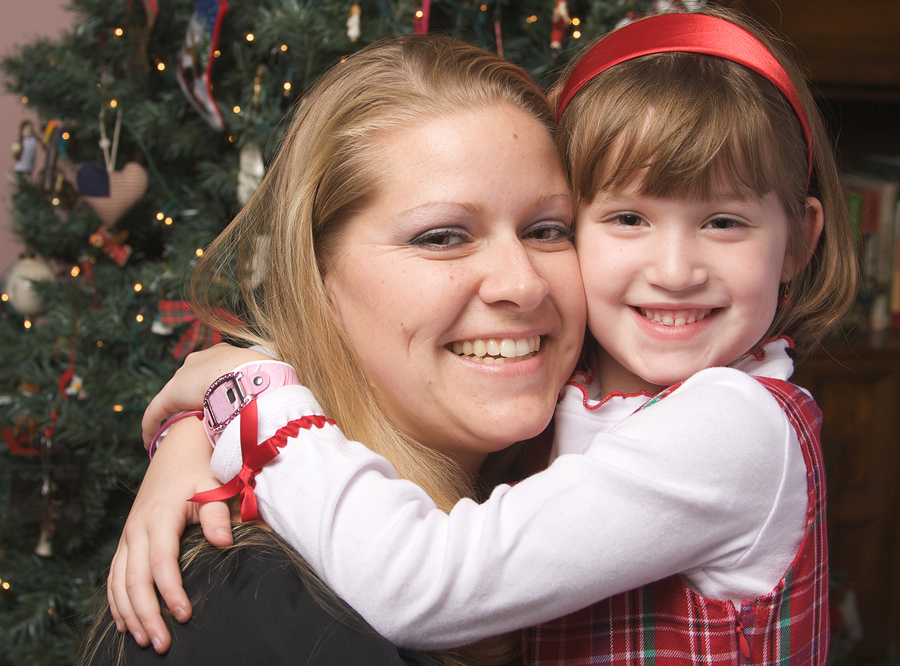 woman hugging a child by Christmas tree